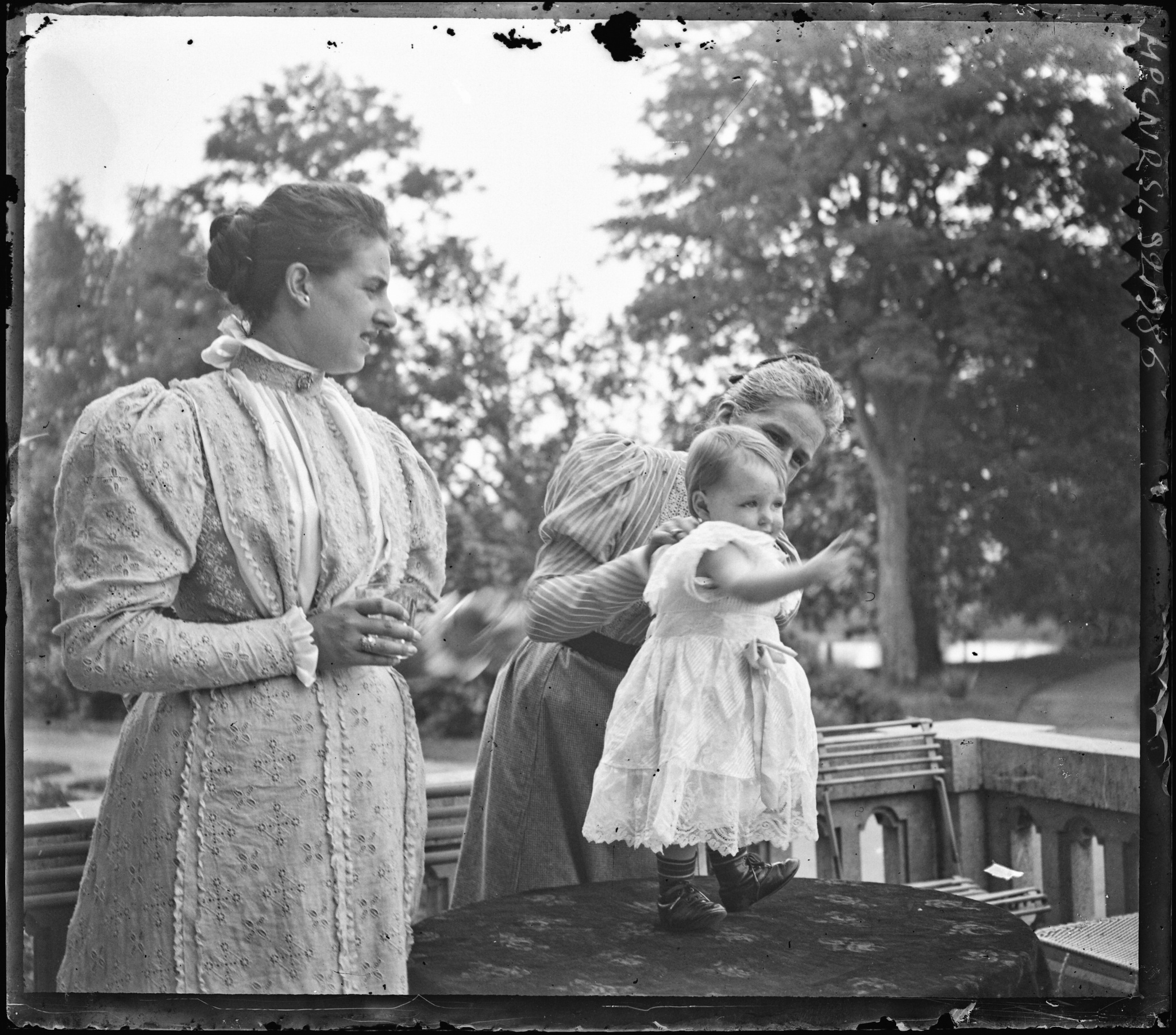 Eusébie et Marguerite avec la petite Marie debout sur une table à l'extérieur