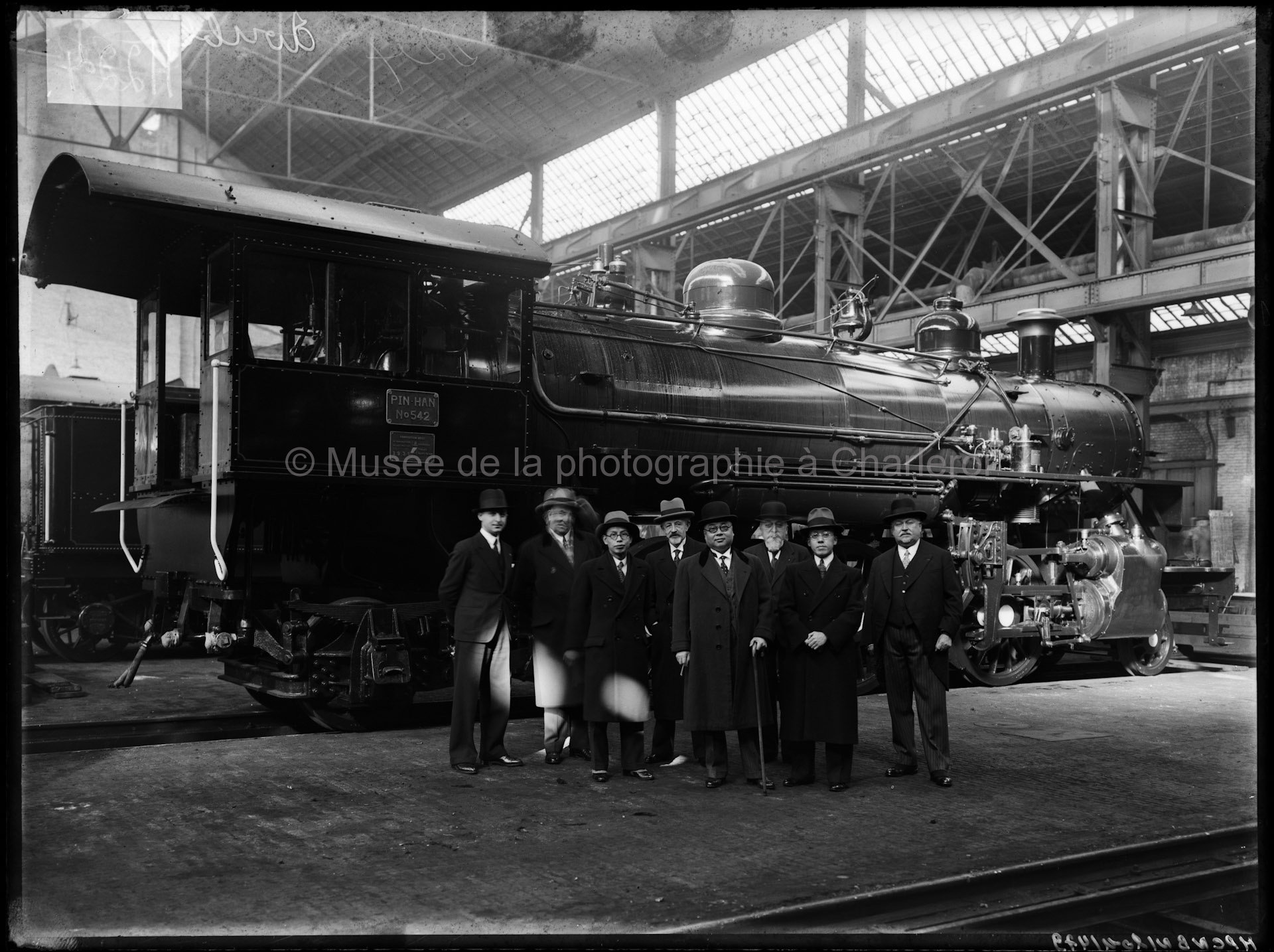 Groupe de huit hommes devant une locomotive